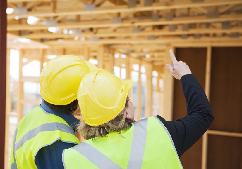 Civil Engineer and Worker Discussing Issues at the Construction Site Pointing at Wood Building Frame